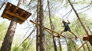 Mann bewältigt einen Parcours in einem Hochseilgarten