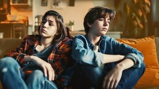 Zwei deprimiert und lustlos schauende Jugendliche sitzen auf einem Sofa