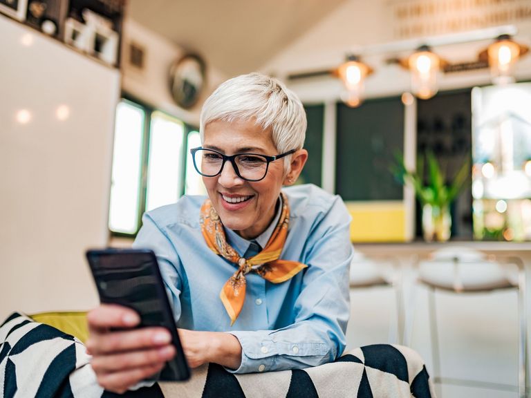 Ältere Frau mit kurzen Haare schaut fröhlich in ein Smartphone