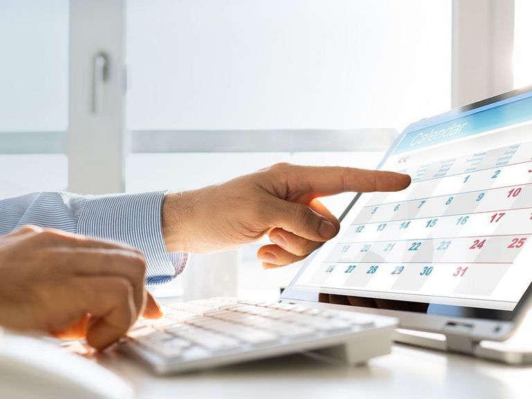 Männerhand zeigt auf einen Terminkalender im Laptop-Bildschirm