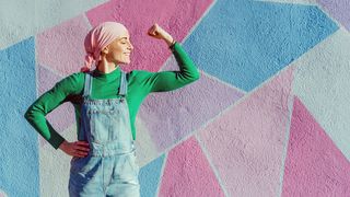 Weltkrebstag Frau mit Krebserkrankung und einem Kopftuch zeigt Muskelpose
