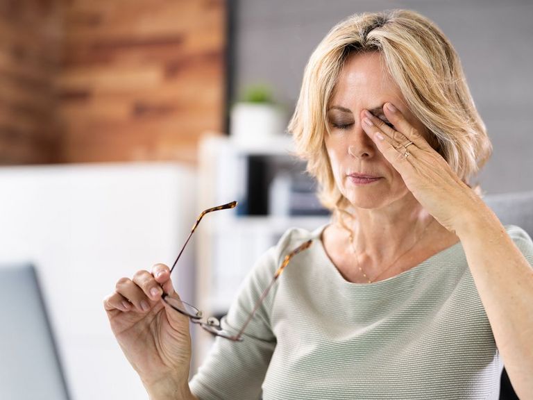 Frau sitzt im Büro vor einem Bildschirm und reibt sich erschöpft die Augen