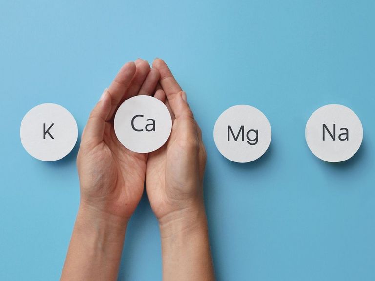 Frauenhände halte kleine runde Schilder mit den chemischen Abkürzungen von vier Mineralstoffen