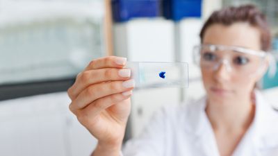 Labormitarbeiterin kontrolliert Test auf einem Objektträger