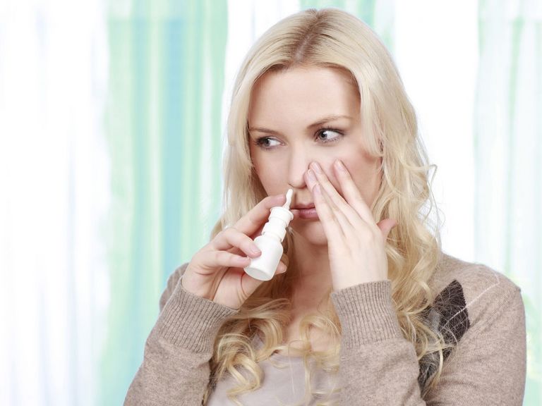 Junge erklältete Frau benutzt Nasenspray