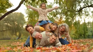 Herbstmeisterschaften Familie liegt aufeinander gestapelt im Herbstlaub