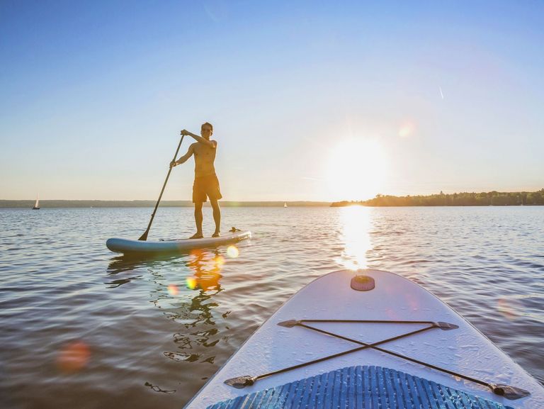 Stand up Paddler auf einem See beim Sonnenuntergang