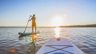 Stand up Paddler auf einem See beim Sonnenuntergang