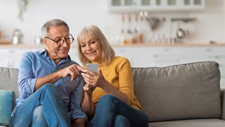 Zugriff auf die ePA Älteres Paar sitzt auf einer Couch und nutzt gemeinsam ein Smartphone