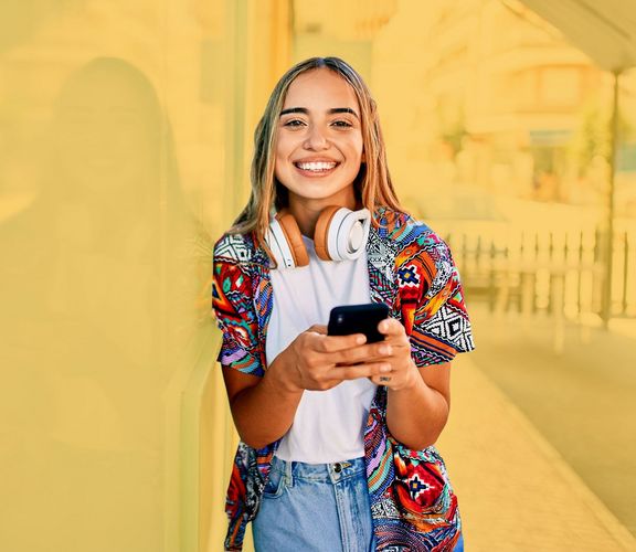 Lächelndes Teenie-Mädchen mit einem Smartphone in der Hand 