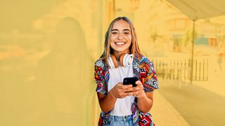 Lächelndes Teenie-Mädchen mit einem Smartphone in der Hand 