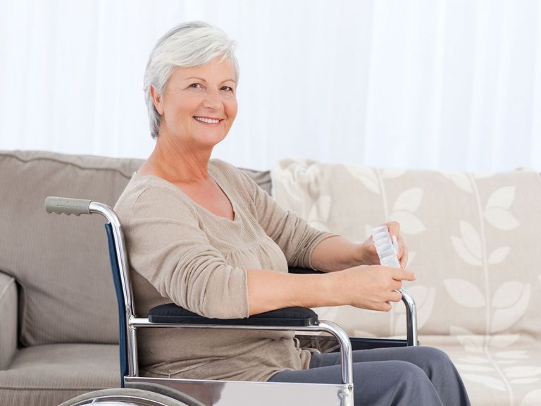 Ältere Frau sitzt zu Hause im Rollstuhl