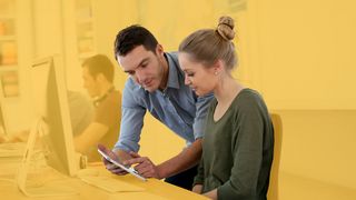 Junge Frau lässt sich am PC und Tablet etwas erklären