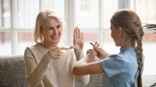 Frau und Kind unterhalten sich lächend in Gebärdensprache