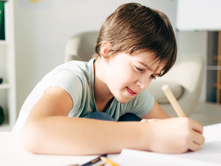 Junge muss sich bei den Schreibaufgaben sehr anstrengen