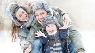 Familie in Winterkleidung lacht in die Kamera