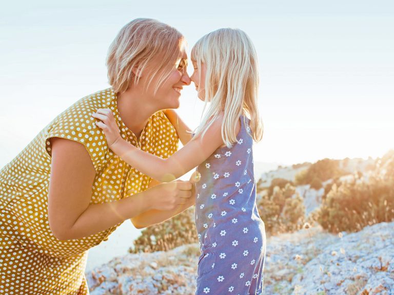 Mutter und Tochter geben sich lachend einen Nasenkuss