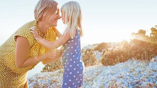 Mutter und Tochter geben sich lachend einen Nasenkuss