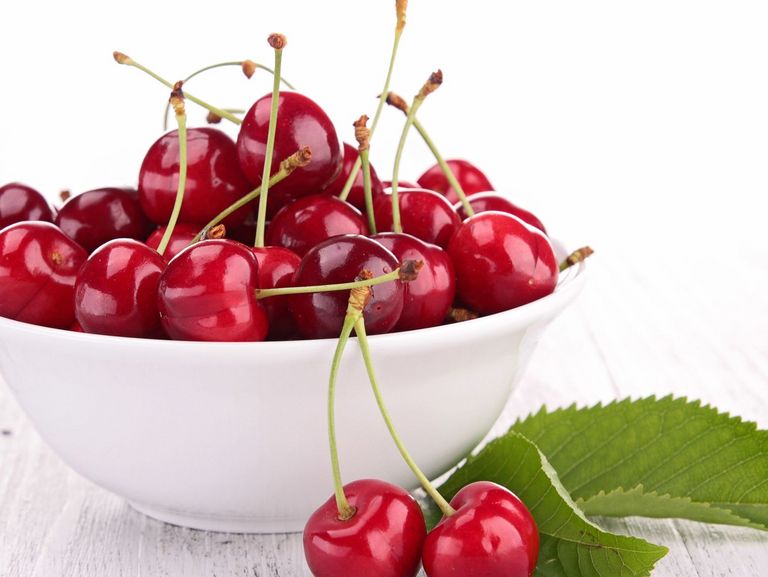 eine weiße Schale mit roten Kirschen