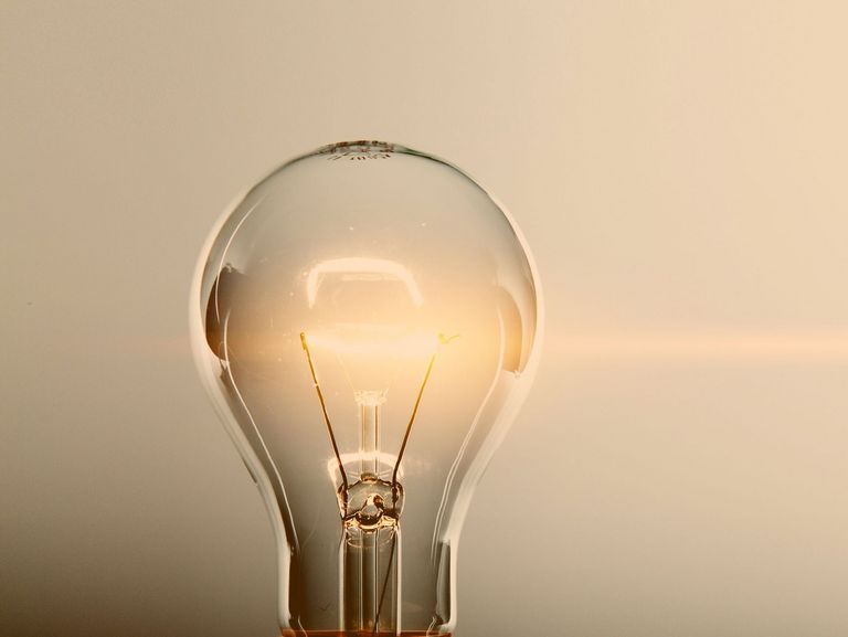 Glimmende Glühlampe vor blau-grauem Hintergrund