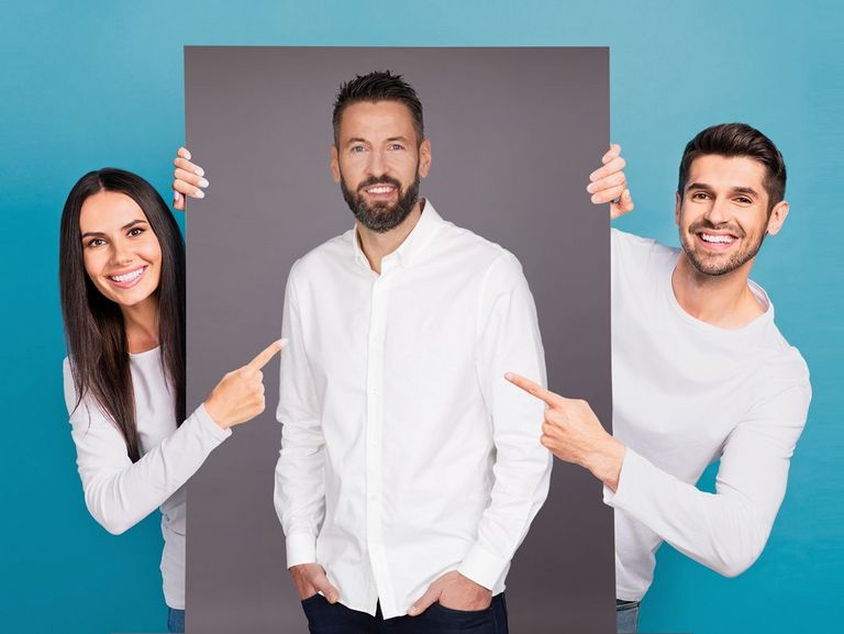 Mann und Frau halten ein sehr großes Bild, auf dem der Gesundheitscoach Bennet Wiegert abgebildet ist