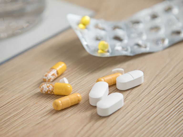Pillen-Blister mit nur noch sehr wenigen gelben Tabletten und Medikamente auf einem hellen Holztisch