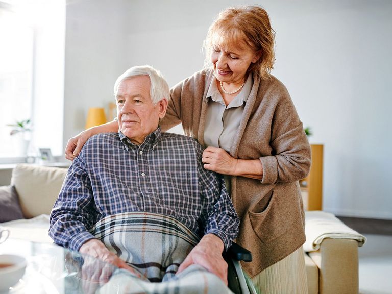 Frau kümmert sich um einen Pflegebedürftigen im Rohlstuhl