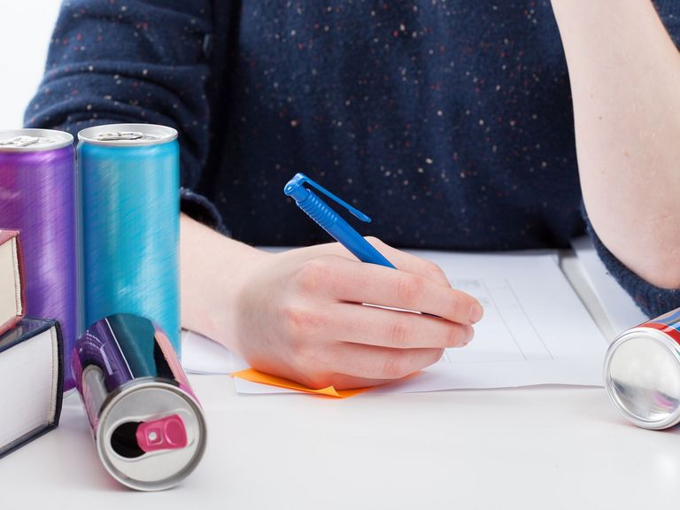 Junger Mann trinkt beim Lernen Energydrinks