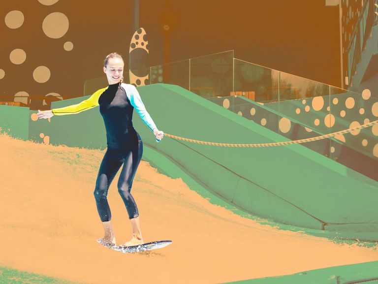 Junge Frau übt das Indoor Surfen mit Sicherungsleine