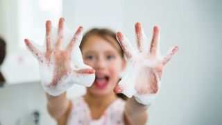 Gesunde Hände Kind zeigt begeistert seine eingeseiften Hände in die kamera