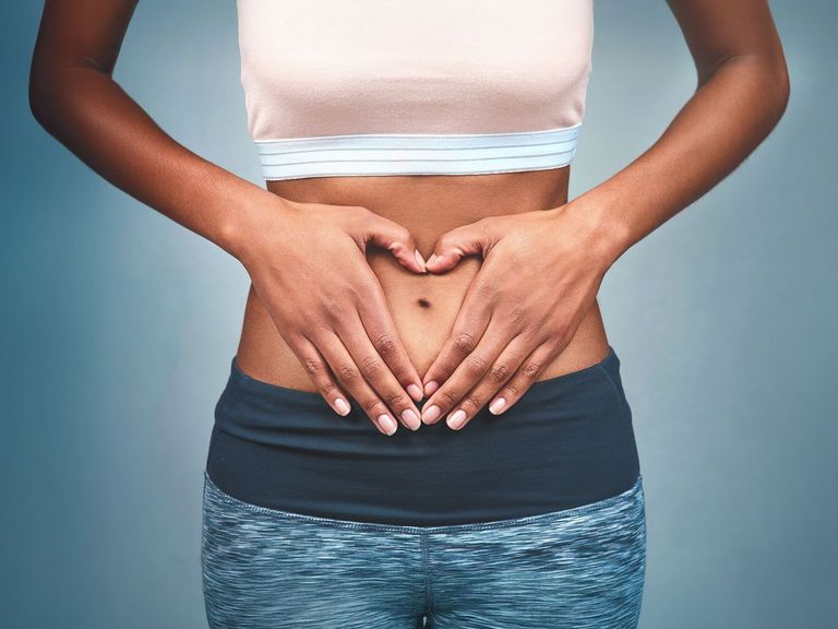 Frau im Sportdress hält ihre Hände auf dem Bauch