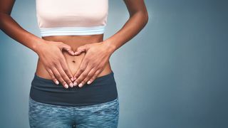 Sport und Verdauung Frau im Sportdress hält ihre Hände auf dem Bauch