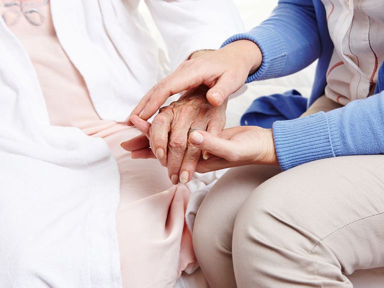 Pflegerin hält Hand von Seniorin