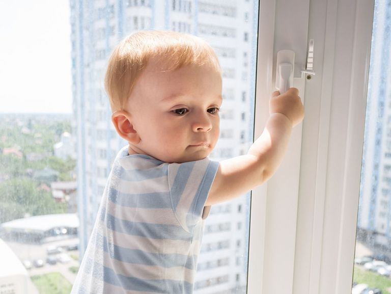 Kleiner junge klettert an einem Fenster herum