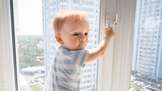 Kleiner junge klettert an einem Fenster herum