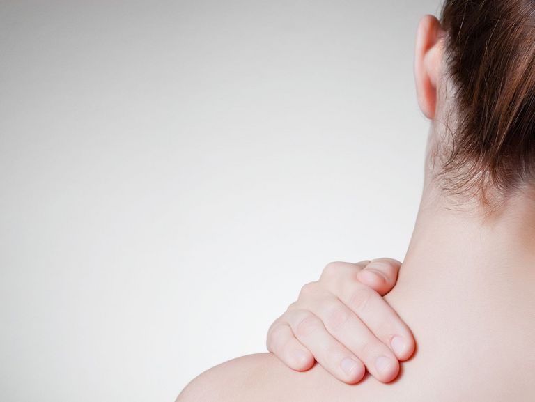 Frau greift sich in den schmerzenden Nacken