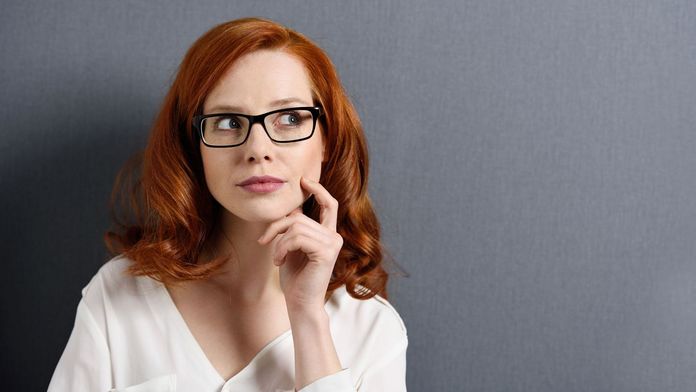 Krankenkassenwahlrecht Frau mit überlegender Miene vor grauem Hintergrund