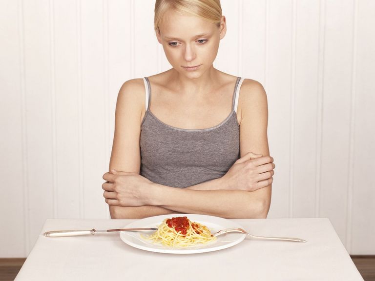 Frau sitzt an einem Tisch und verweigert das Essen