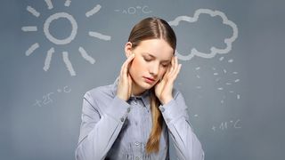 Das Wetter im Gefühl Frau hält sich aufgrund des Wetter die Hände an die Schläfen
