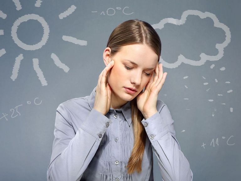 Frau hält sich aufgrund des Wetter die Hände an die Schläfen