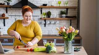 Online-Ernährungsberatung Frau bereitet unter Anleitung per Laptop Essen in einer Küche zu