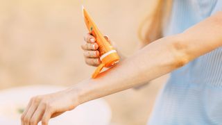 Hautschutz im Sommer Frau macht aus einer Tube etwas Sonnenschutzcreme auf ihren ausgestreckten Unterarm