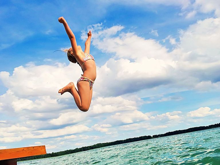 Mädchen springt begeistern in einen See