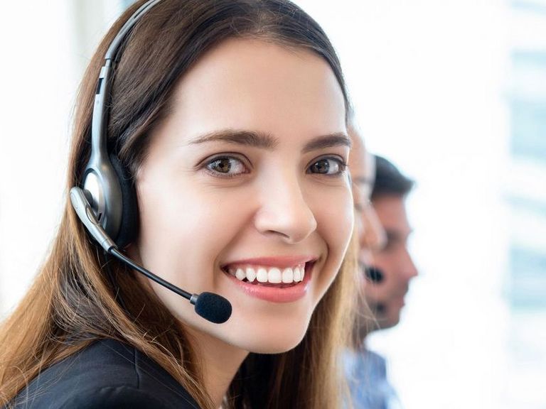 Mitarbeiterin mit einem Headset lächelt in die Kamera