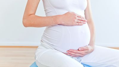 Frau umfasst ihren Babybauch