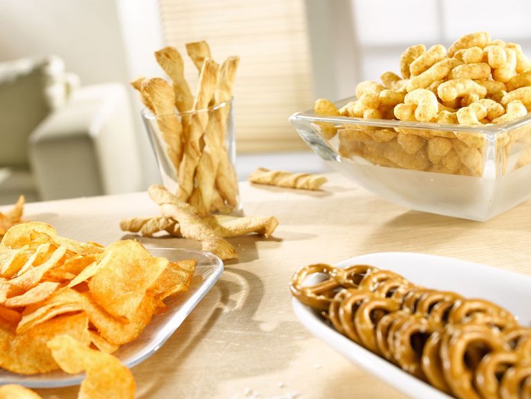 Chips, Salzbrezeln und Erdnusflips auf einem Tisch