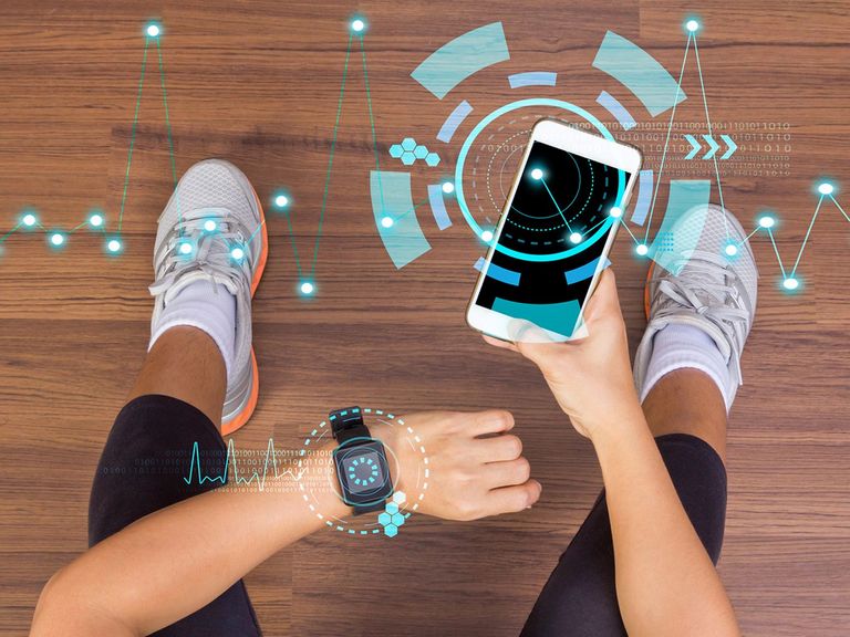 Frau hält beim Sport ein Smartphone und eine Smartwatch