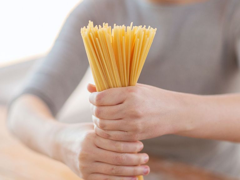 Frau hält Spaghetti als Bündel fest