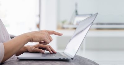 Frau zeigt mit dem Zeigefinger auf den Bildschirm eines Laptops