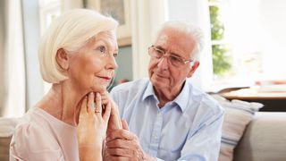 Ältere Frau abwesend in Gedanken und ihr Mann in Sorge neben ihr